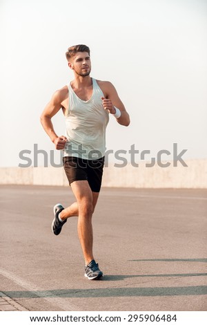 Finding inspiration in his training. Handsome young muscular man running along the road