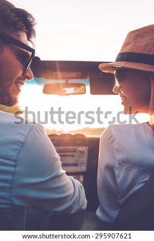 Enjoying every minute together. Rear view of happy young couple looking at each other while sitting inside of their convertible