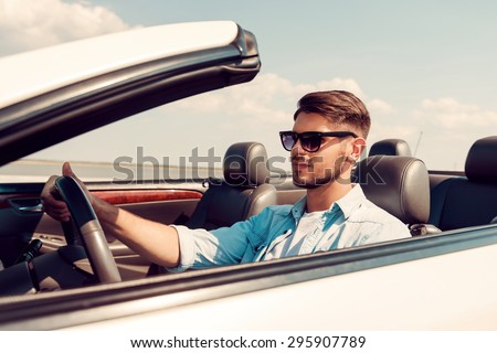 Feeling freedom. Confident young man looking forward while driving his white convertible