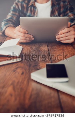 Smart technologies for successful life. Close-up of man holding digital tablet while sitting at his working place