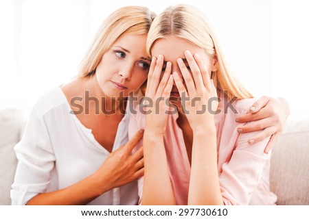 I will always be with you in any situation! Beautiful mature woman consoling her crying daughter while sitting on sofa