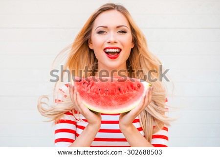 Slice of summer goodness. Beautiful young woman holding slice of watermelon and smiling while standing outdoors