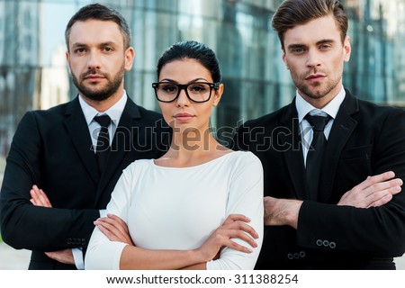 Faces of new business. Three confident business people keeping arms crossed and looking at camera while standing outdoors