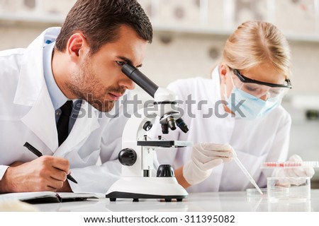 Improving modern medicine. Two young scientists making experiments while sitting in the laboratory