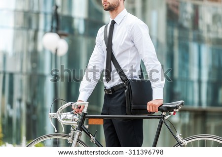 Eco-friendly way to get to work.Cropped image of young businessman holding hands on his bicycle while standing outdoors