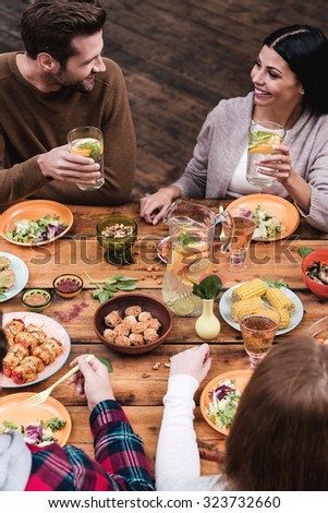 Dining with friends. Top view of four people having dinner together while sitting at the rustic wooden table