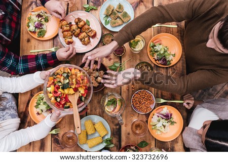 Friends having dinner. Top view of four people having dinner together while sitting at the rustic wooden table