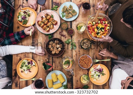 Enjoying dinner together. Top view of four people having dinner together while sitting at the rustic wooden table