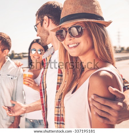 Enjoying time with friends. Group of young happy people talking to each other while beautiful woman looking at camera and smiling