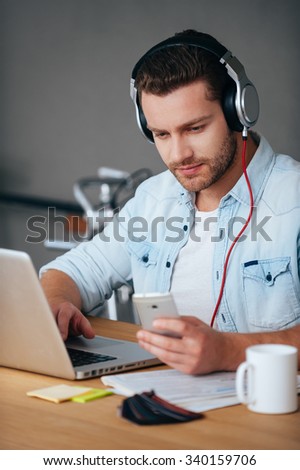 Enjoying his music break. Confident young man in headphones listening to the music while sitting at his working place in office