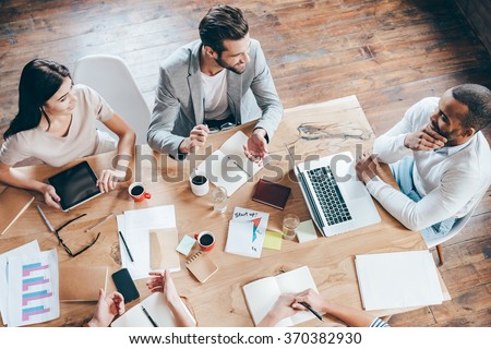 Team communication. Top view part of group of five people discussing something with smile while sitting at the office table