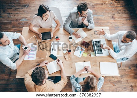 Results and teamwork. Top view of group of six people discussing something while sitting at the office table