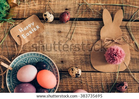 Happy Ester! Top view of colored Easter eggs and Easter decorations lying on wooden rustic table