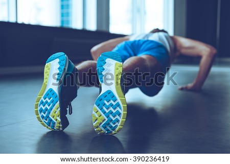 Perfect push-up. Rear view of young man in sportswear doing push-up at gym