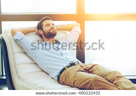 Time to relax. Handsome young man holding hands behind head while sleeping on the couch