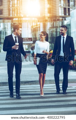 On the way to work. Full length of three smiling business people talking to each other while crossing the street