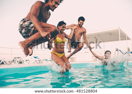 Enjoying pool party with friends. Group of beautiful young people looking happy while jumping into the swimming pool together
