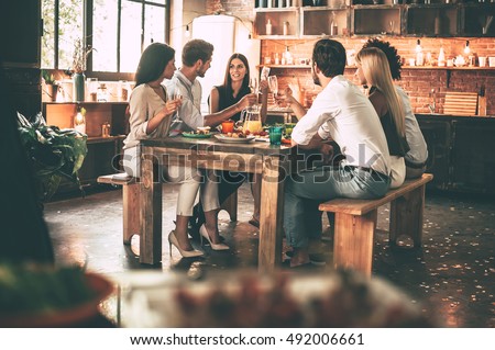 Enjoying dinner with friends. Group of cheerful young people enjoying dinner while sitting on the kitchen together