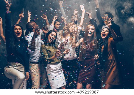 Party fun. Group of beautiful young people throwing colorful confetti and looking happy