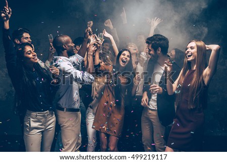 Enjoying carefree time together. Group of beautiful young people throwing colorful confetti and looking happy