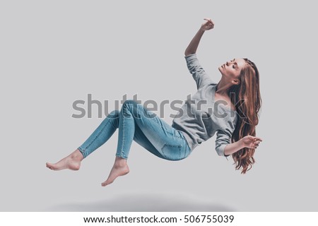 Hovering beauty. Full length studio shot of attractive young woman hovering in air and keeping eyes closed