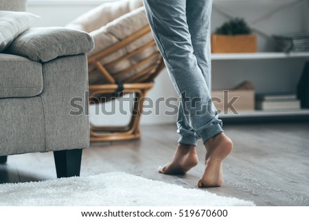 Warm floor concept. Close-up of female legs stepping by hardwood floor at home