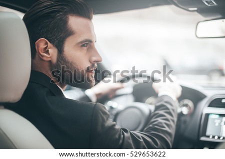 Businessman in car. Rear view of young handsome man looking on the right while driving a car