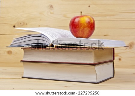 Books with apple on wood background