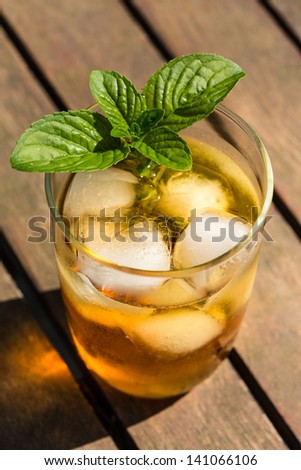 Glass of iced tea with ice-cubes and mint leaves, close-up