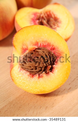 Peaches and half a peach cut to reveal the stone