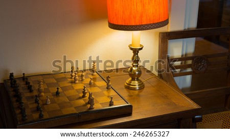 Old chessboard on writing desk and Soft Light of A desk Lamp