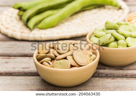 Dried beans in the clay dish. Fresh green beans and bean pods in the background