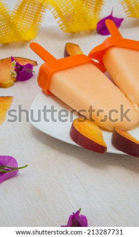 Homemade peach ice cream with pieces of fresh peach. Peaches ni the background
