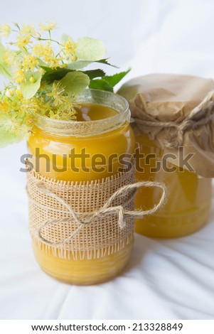 Two glasses of linden honey and fresh linden flowers