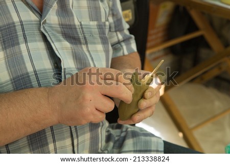 A man is modeling a figurine from clay. Body parts