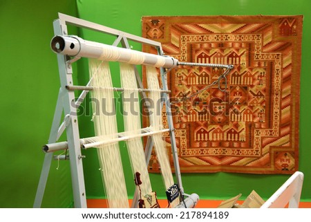 Tunis, Tunisia - December 15, 2013: National Exhibition of Handmade work in Tunis. Metal loom for weaving carpets with the Margoum carpet background