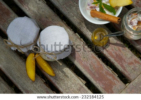 Two glasses of homemade yogurt with pieces of peach on an old wooden surface. Honey and fresh yogurt in the dish. Top view.Background