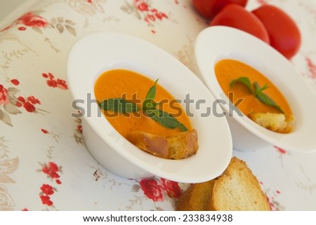 Light lunch soup-tomato soup with croutons in white plates on a flower print table cloth