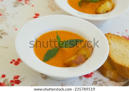Light lunch soup-tomato soup with croutons in white plate on a flower print table cloth