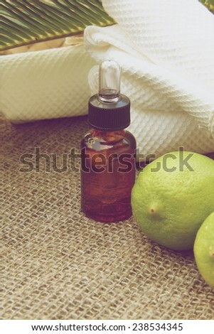 A dropper bottle of lemon essential oil. Fresh lemon in the background