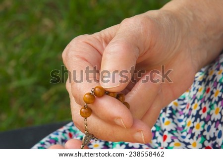 Christian prayer beads in the hand of old woman