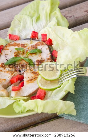 Light dinner- grilled swordfish with fresh salad leaves and vegetables. Close up