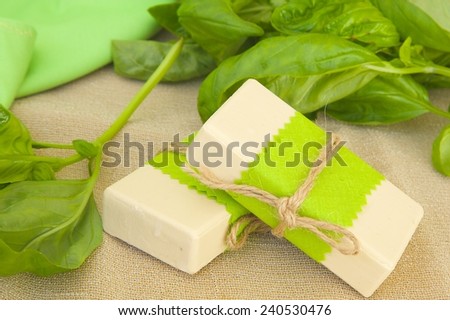 Two soap bars with basil essential oil. Fresh basil leaves in the background