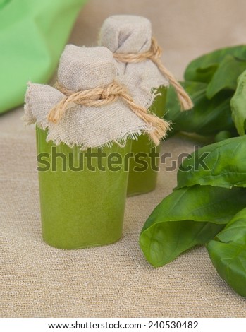 Body scrub with basil essential oil. Fresh basil leaves in the background.