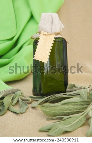 A bottle of sage oil. Fresh sage leaves in the background