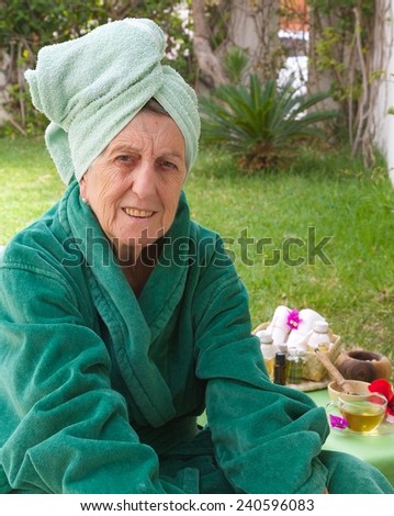 A senior woman between 70 and 80 years old is ready to go through rejuvenating facial procedures. Table with spa skin care products in the background