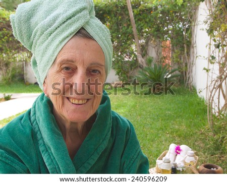 A smiling senior woman between 70 and 80 years old is ready to go through rejuvenating facial procedures. Table with spa skin care products in the background