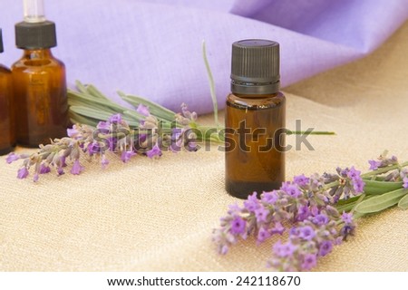 A dropper bottle of lavender essential oil. Lavender twigs in the background.