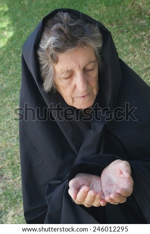 An old woman dressed in black is begging for bread