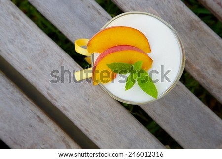 Milk dessert - sweet ricotta cheese with peach in a glass dessert bowl. Top view